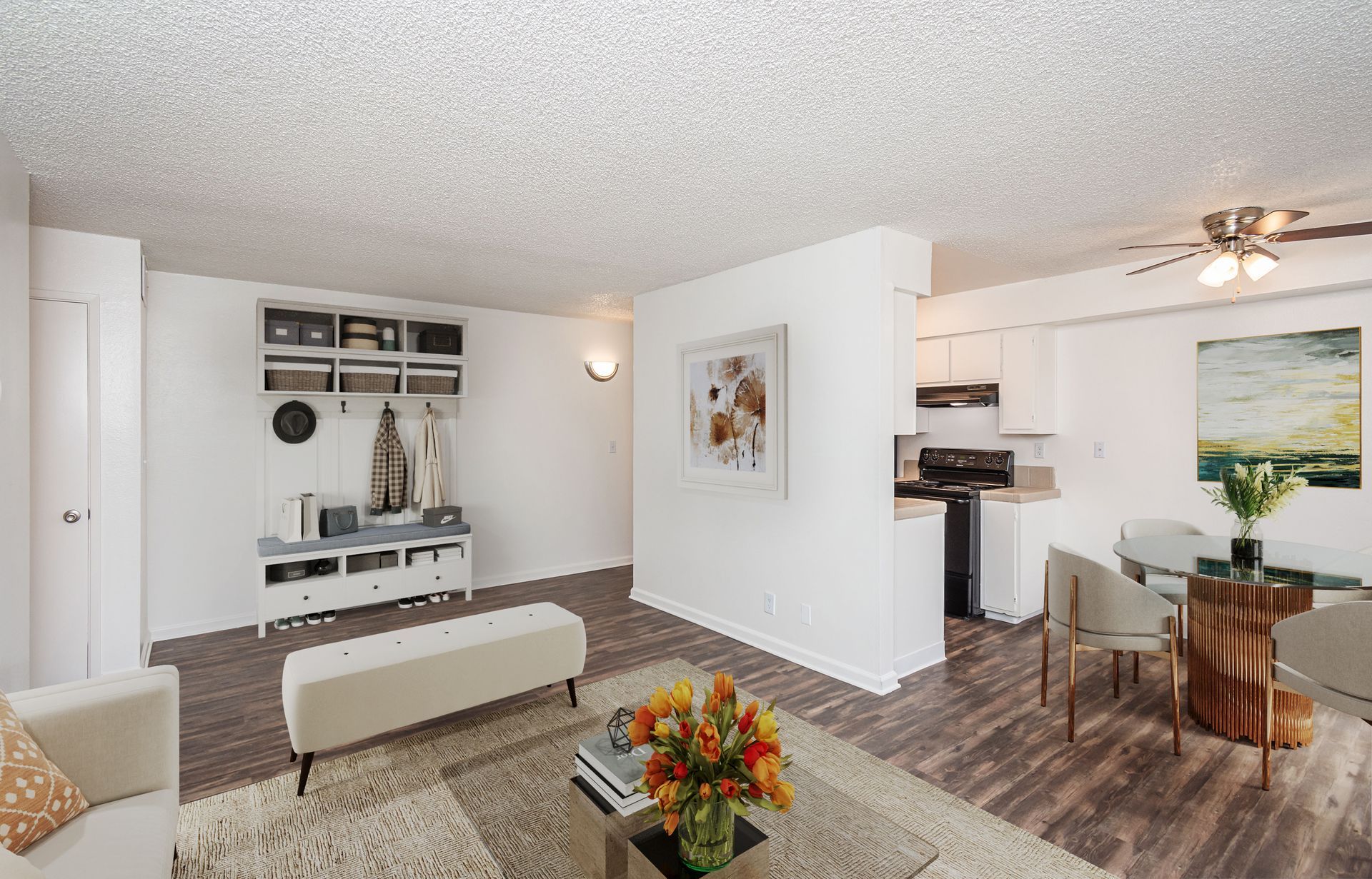 A living room with a couch , table , chairs and a ceiling fan.