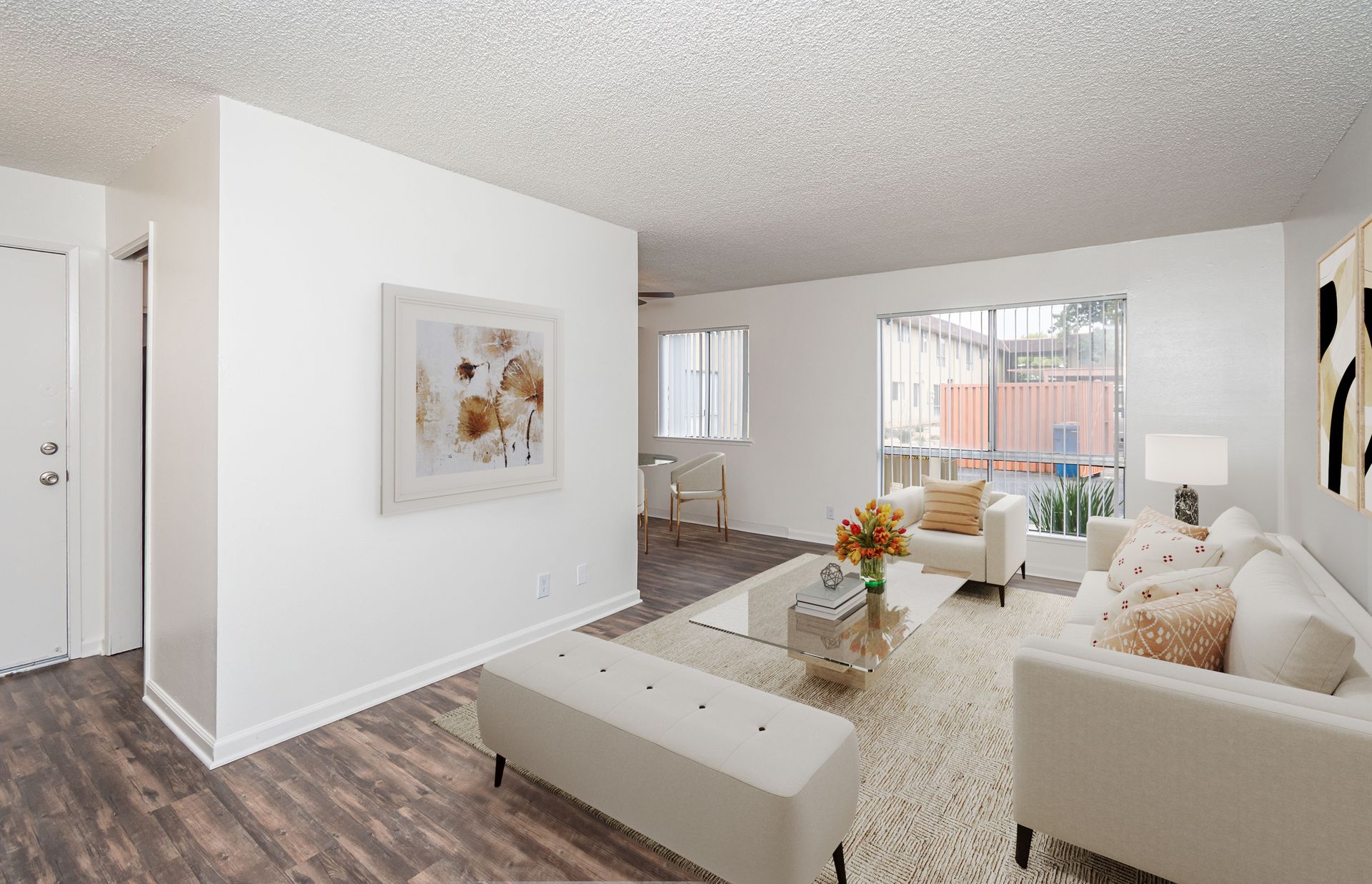 A living room with a couch , chair , coffee table and a painting on the wall.