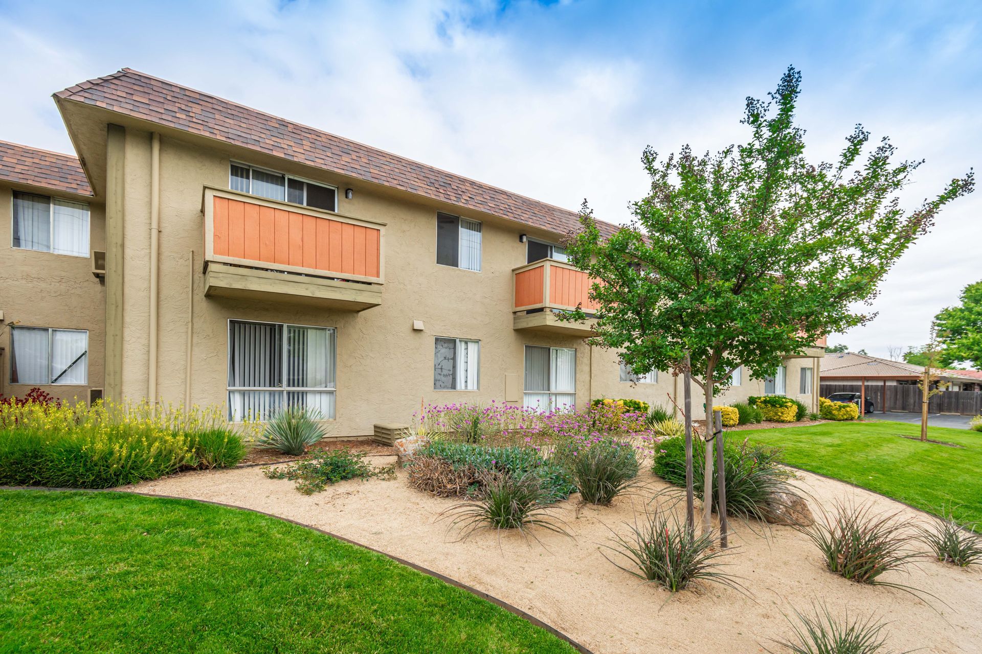 A large apartment building with a lush green lawn in front of it