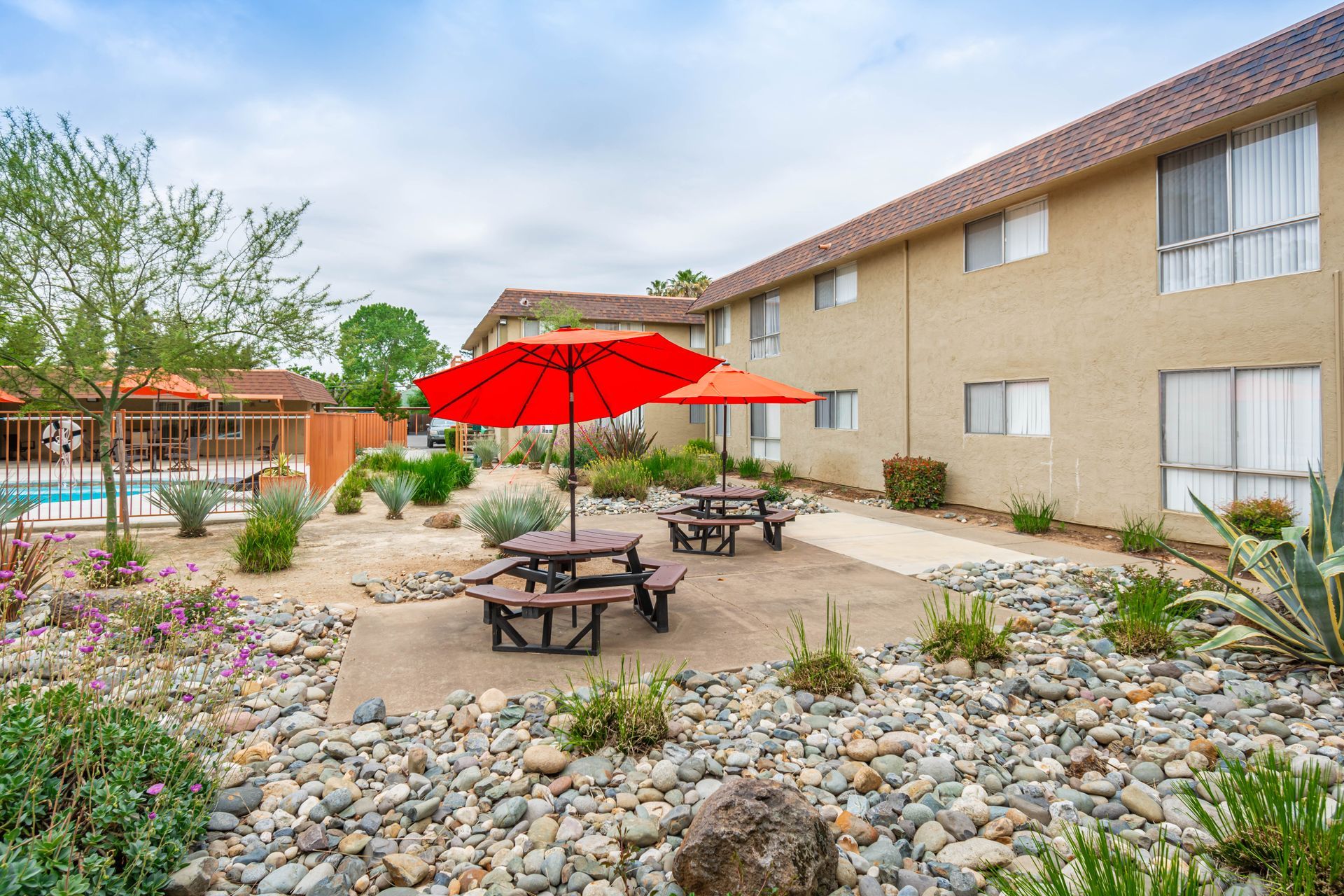 A picnic area with tables and umbrellas in front of a building.