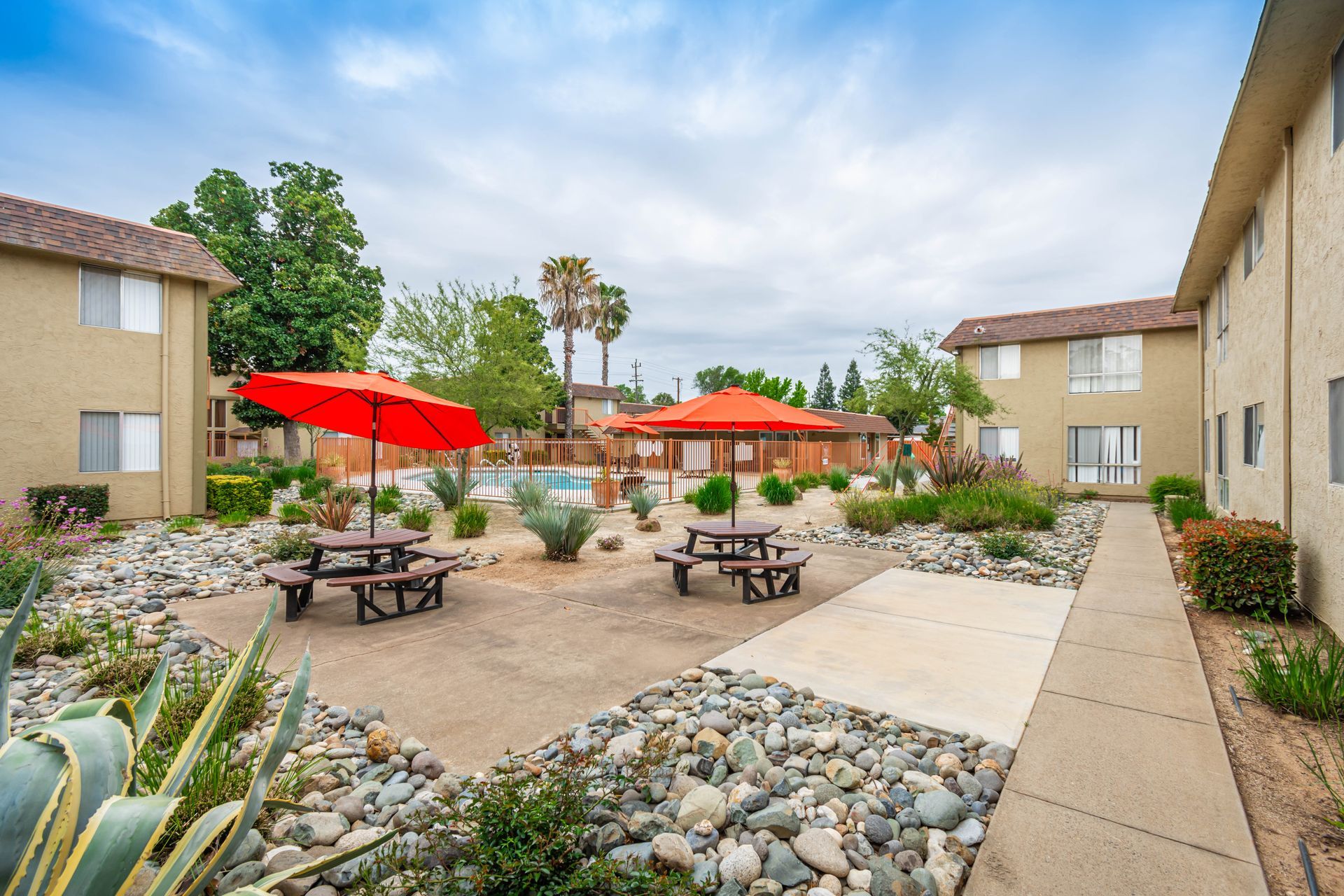 A courtyard with picnic tables and umbrellas in front of a building.