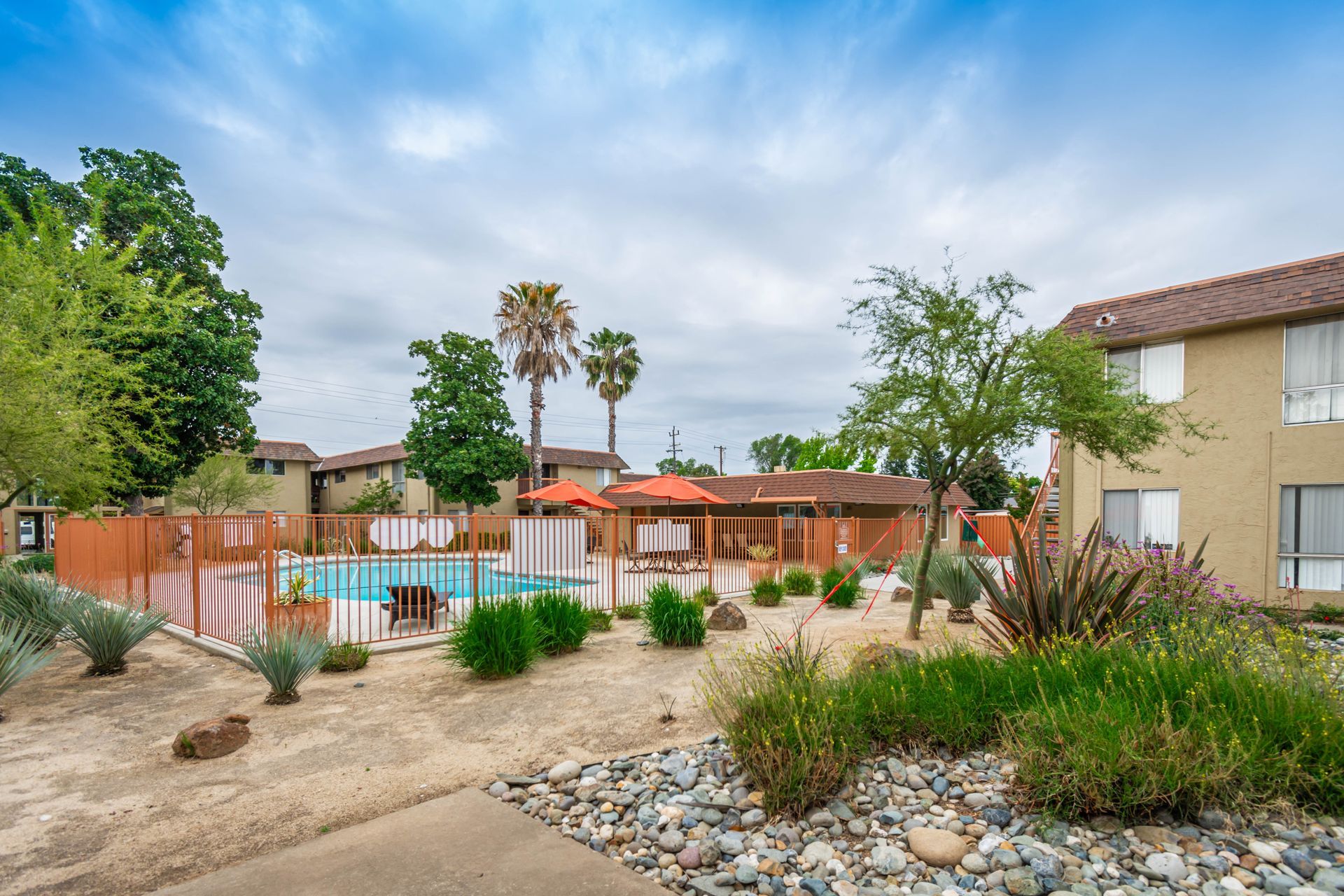 A swimming pool is surrounded by a fence in a residential area.