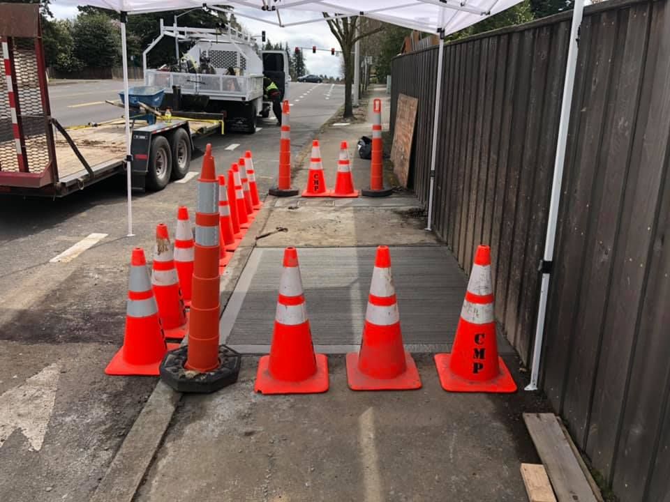 A row of orange and white traffic cones on a sidewalk