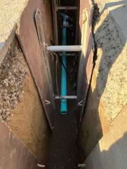 A man is holding a red hose in a hole in the ground