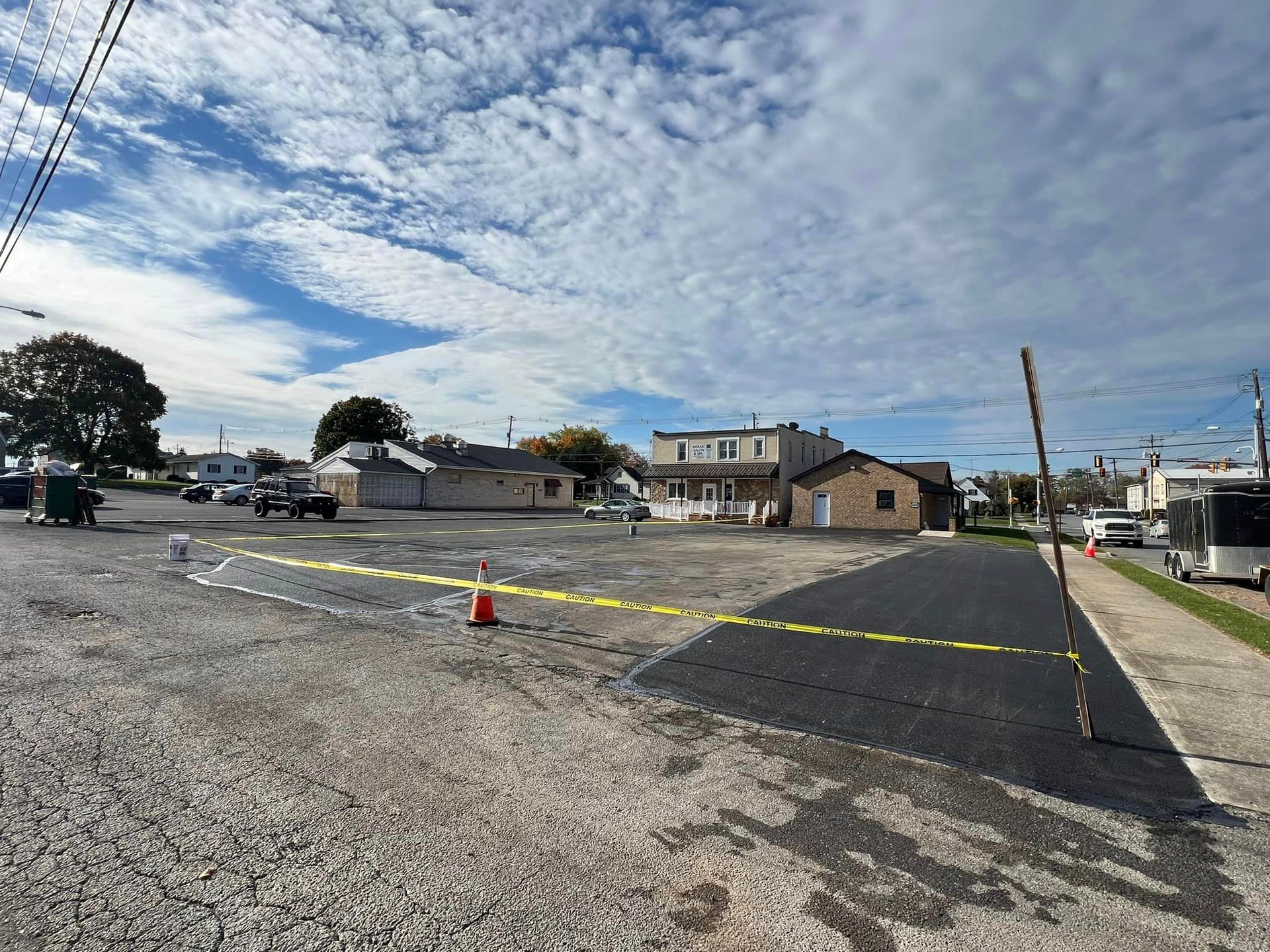 A parking lot with a house in the background and a lot of cars parked on the side of the road.