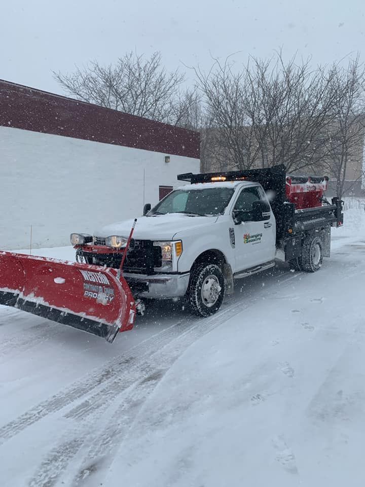 White snowplow truck clearing snow, red plow blade, winter scene.