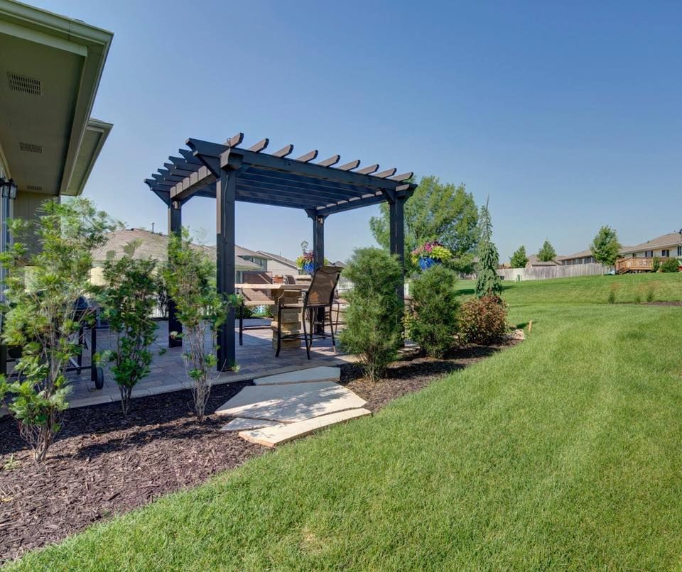Brick house entrance with a paved path, flower planters, and landscaping.