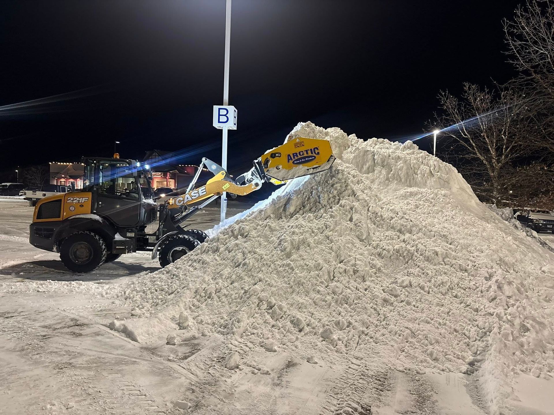 White snowplow truck clearing snow, red plow blade, winter scene.