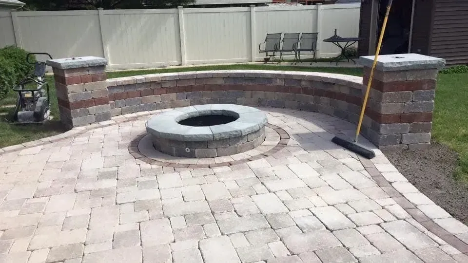 Fire pit area with brick pavers, low wall, and columns.