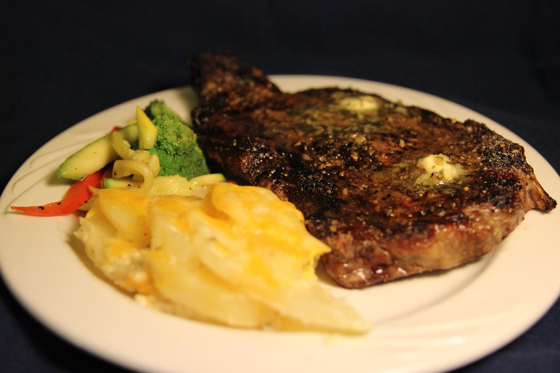 A white plate topped with a steak and vegetables