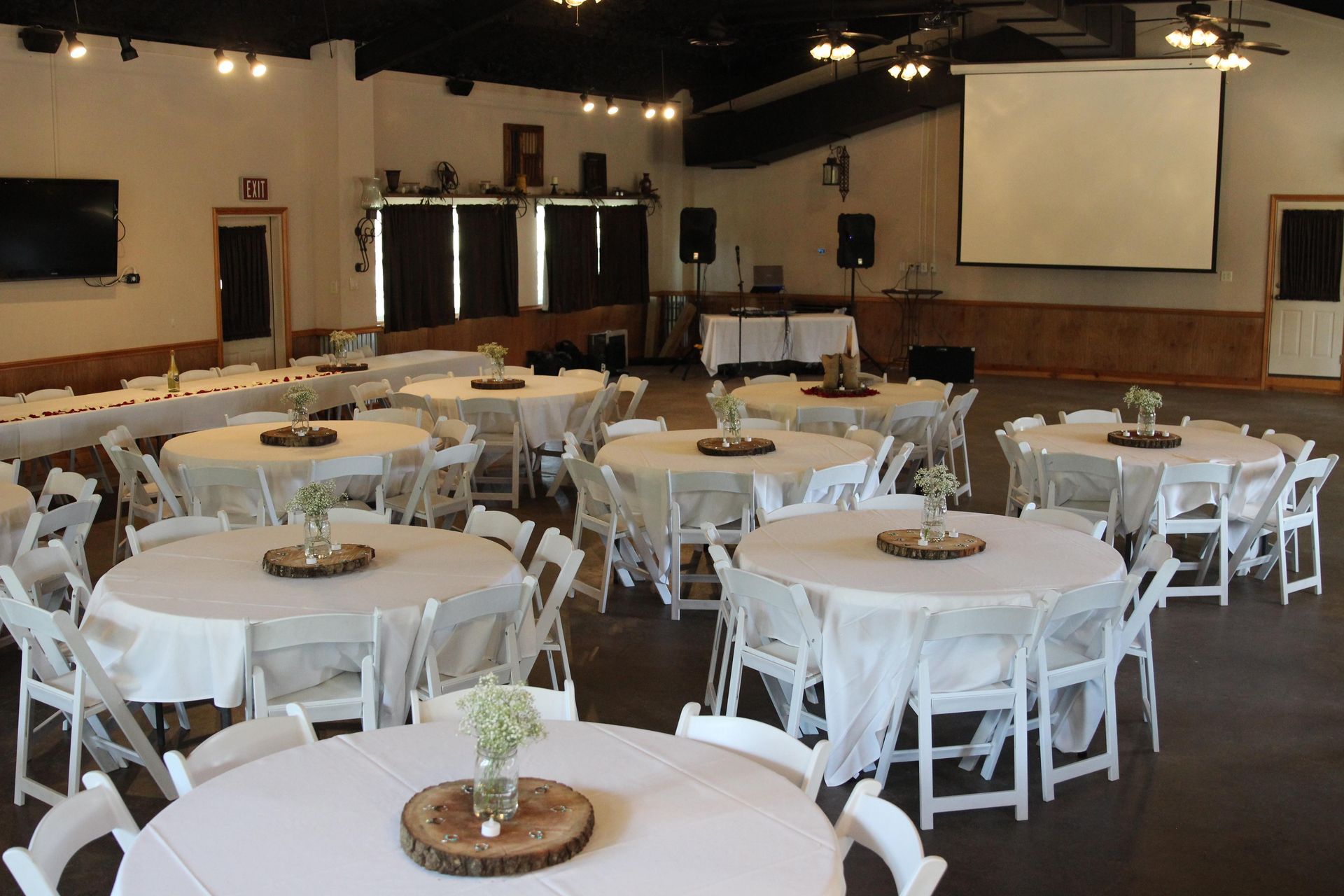 A large room with tables and chairs and a projector screen