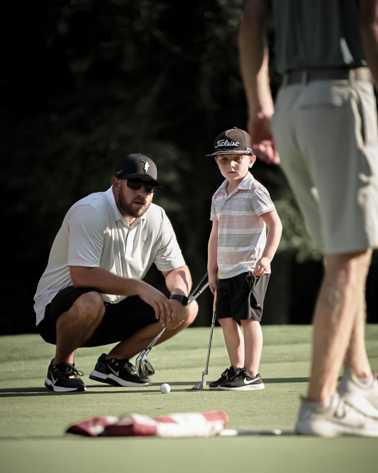 A man and a little boy are playing golf on a green.