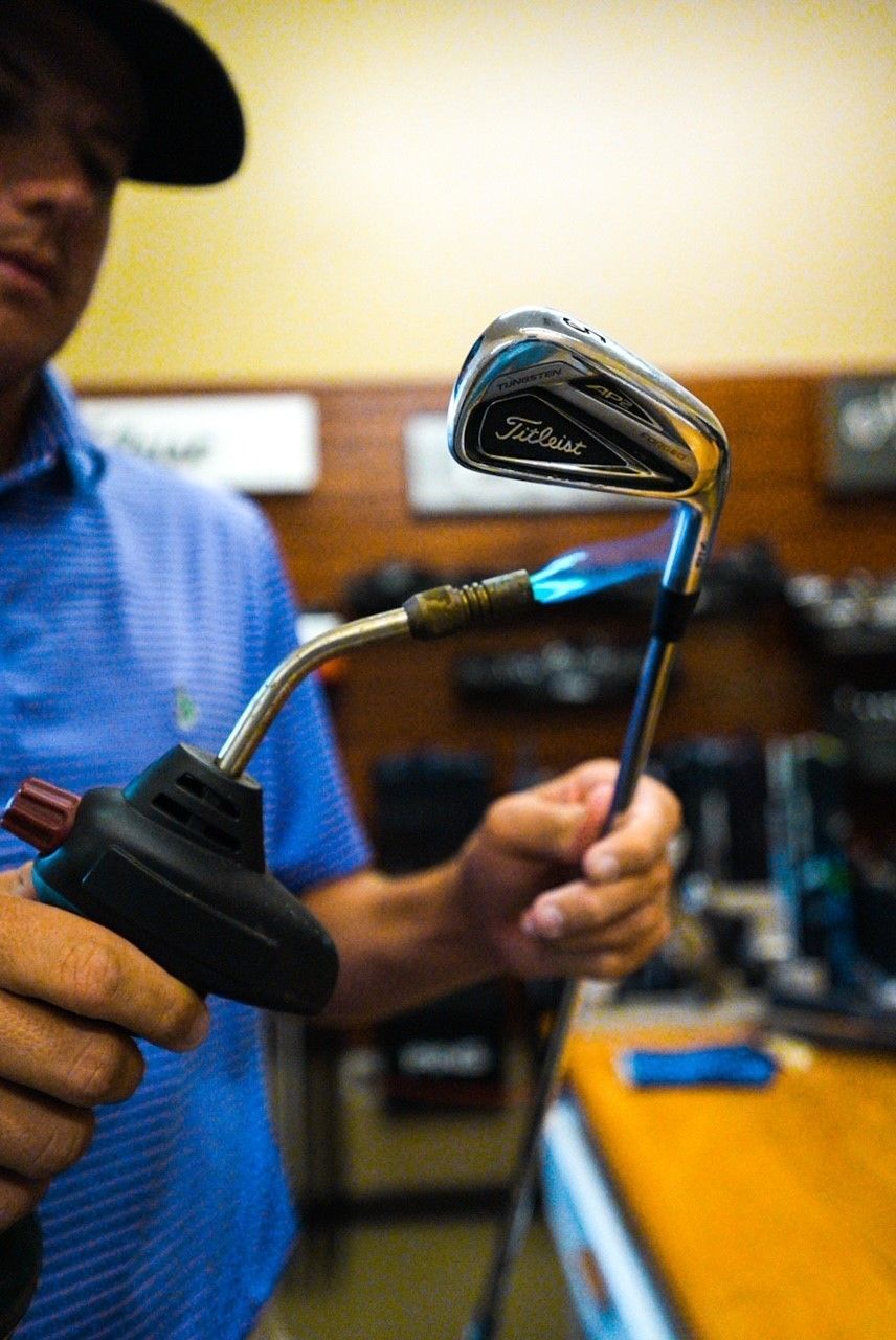 A man is holding a golf club with a torch attached to it.