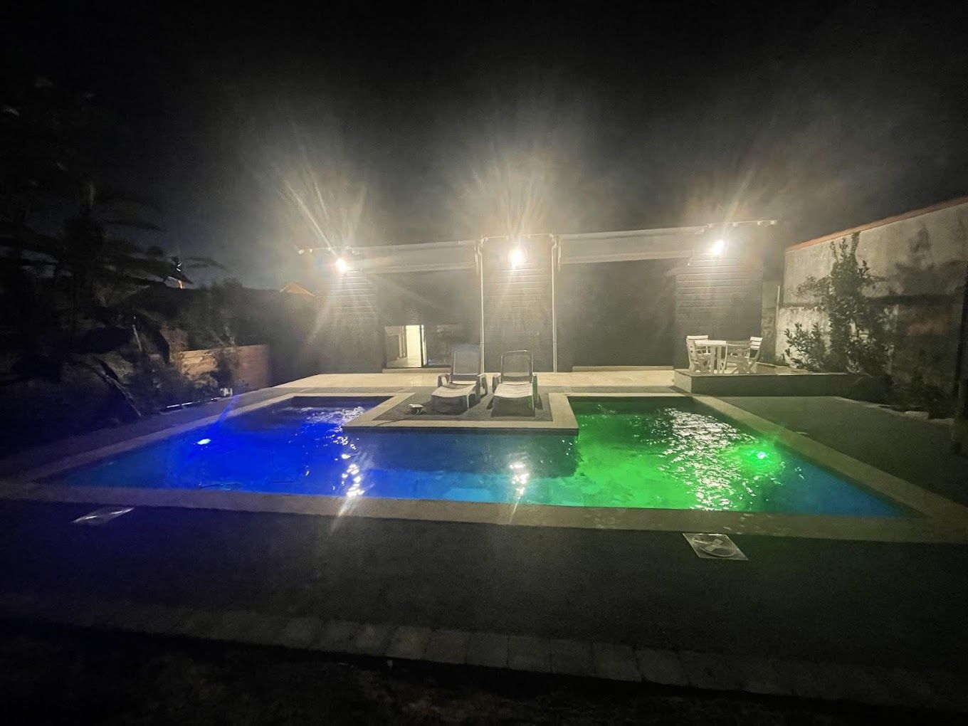 une grande piscine est éclairée la nuit.