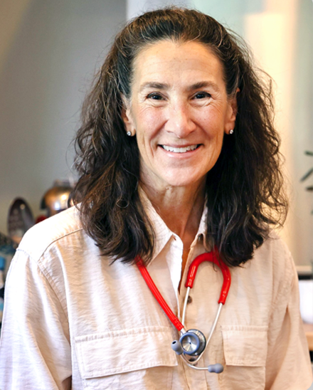 Dr. Bonnie Feola with stethoscope, smiling, wearing tan shirt.