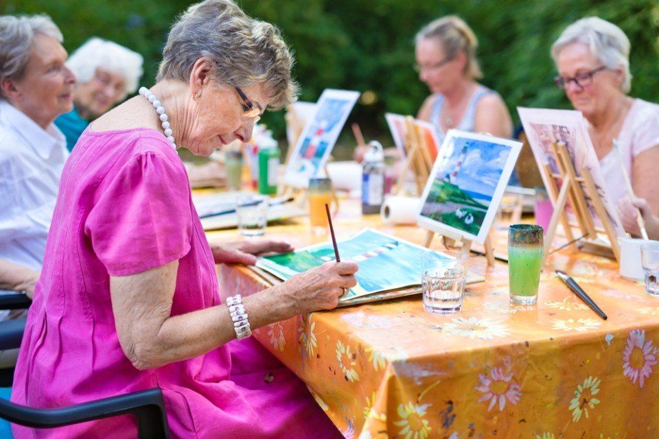 anziana mentre dipinge durante il corso di pittura