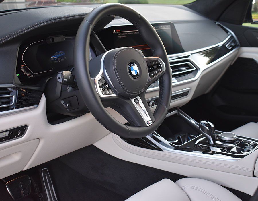 Interior of a BMW car with black and white leather seats, a steering wheel, and dashboard.