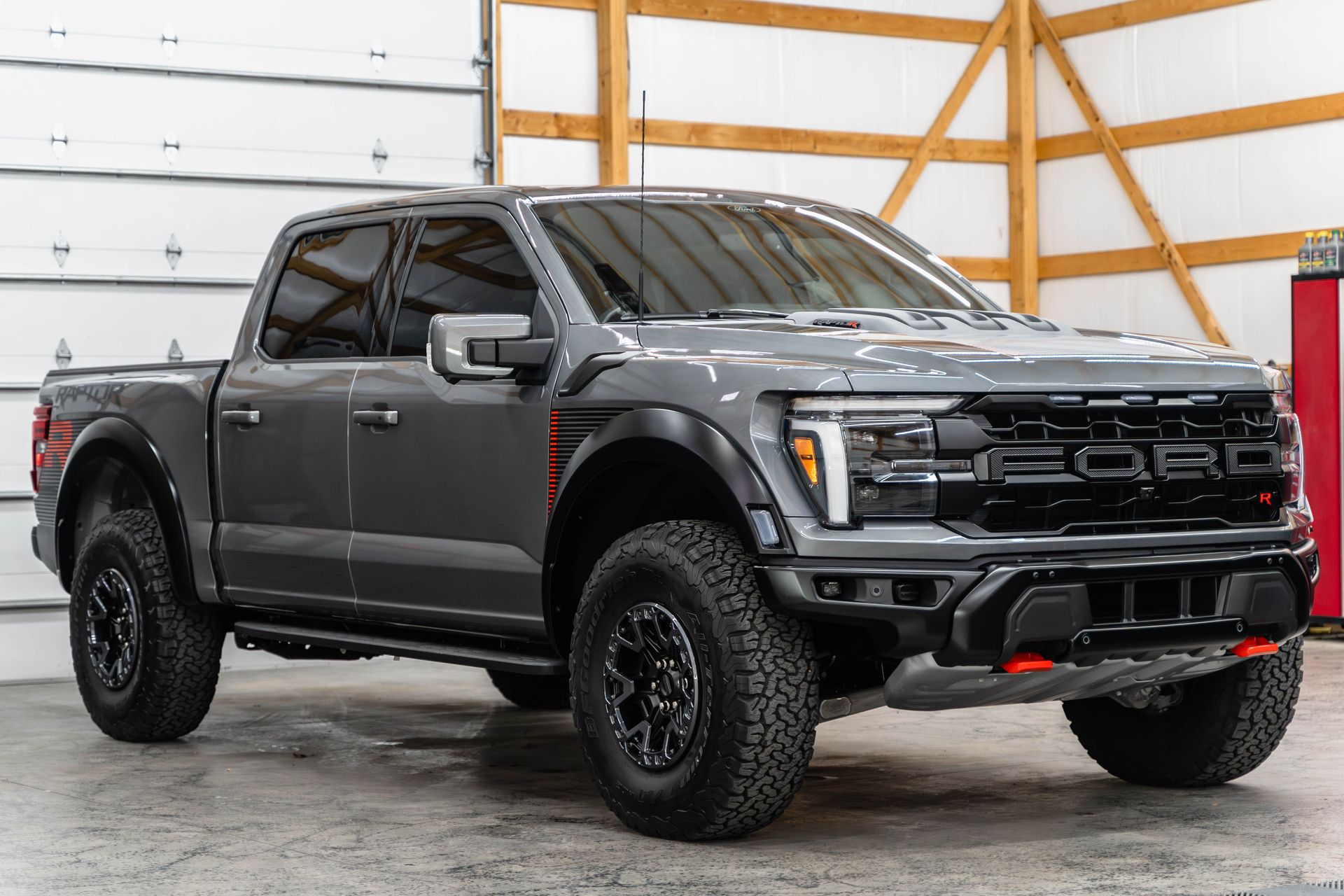 A gray ford raptor truck is parked in a garage.