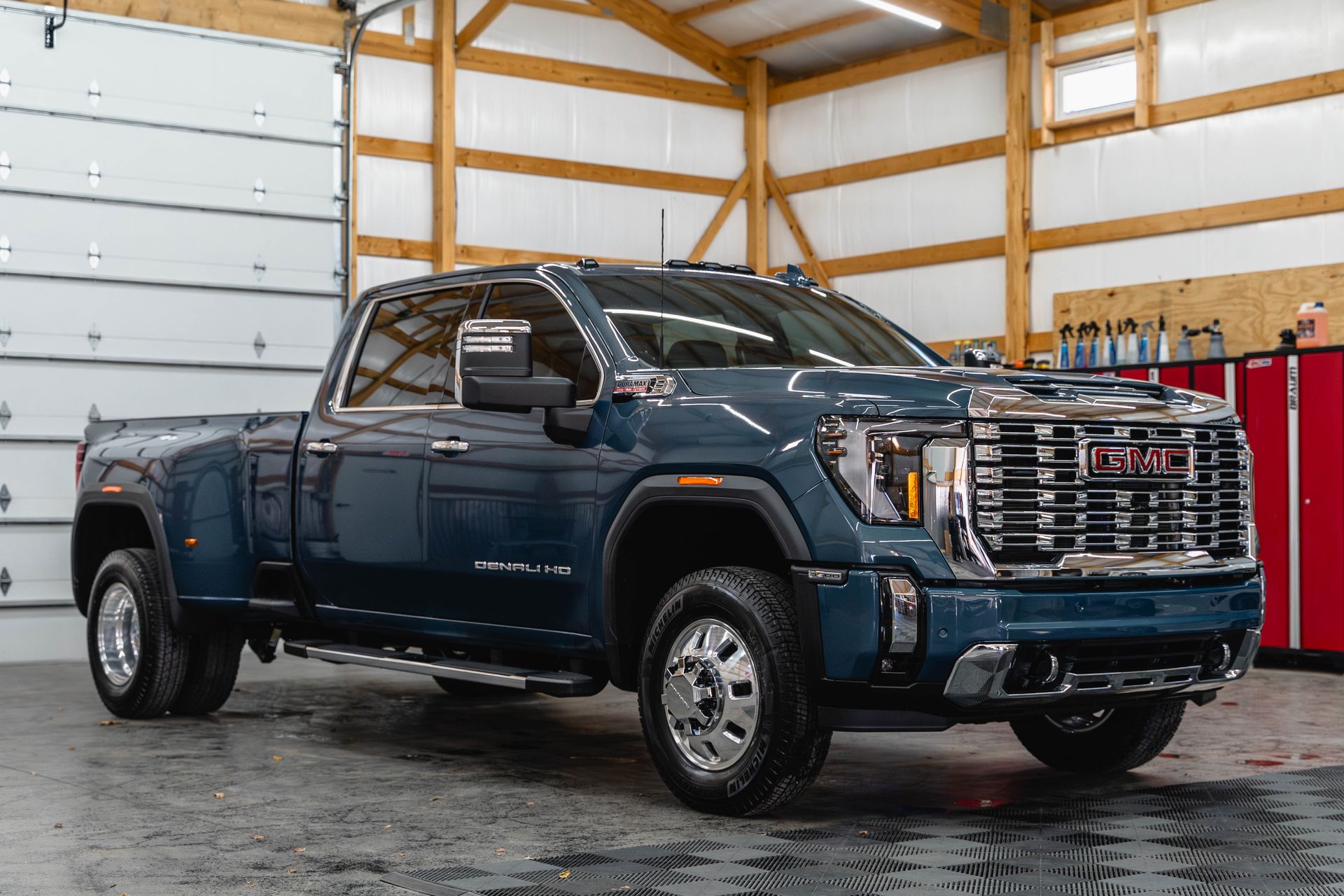 A blue gmc sierra pickup truck is parked in a garage.