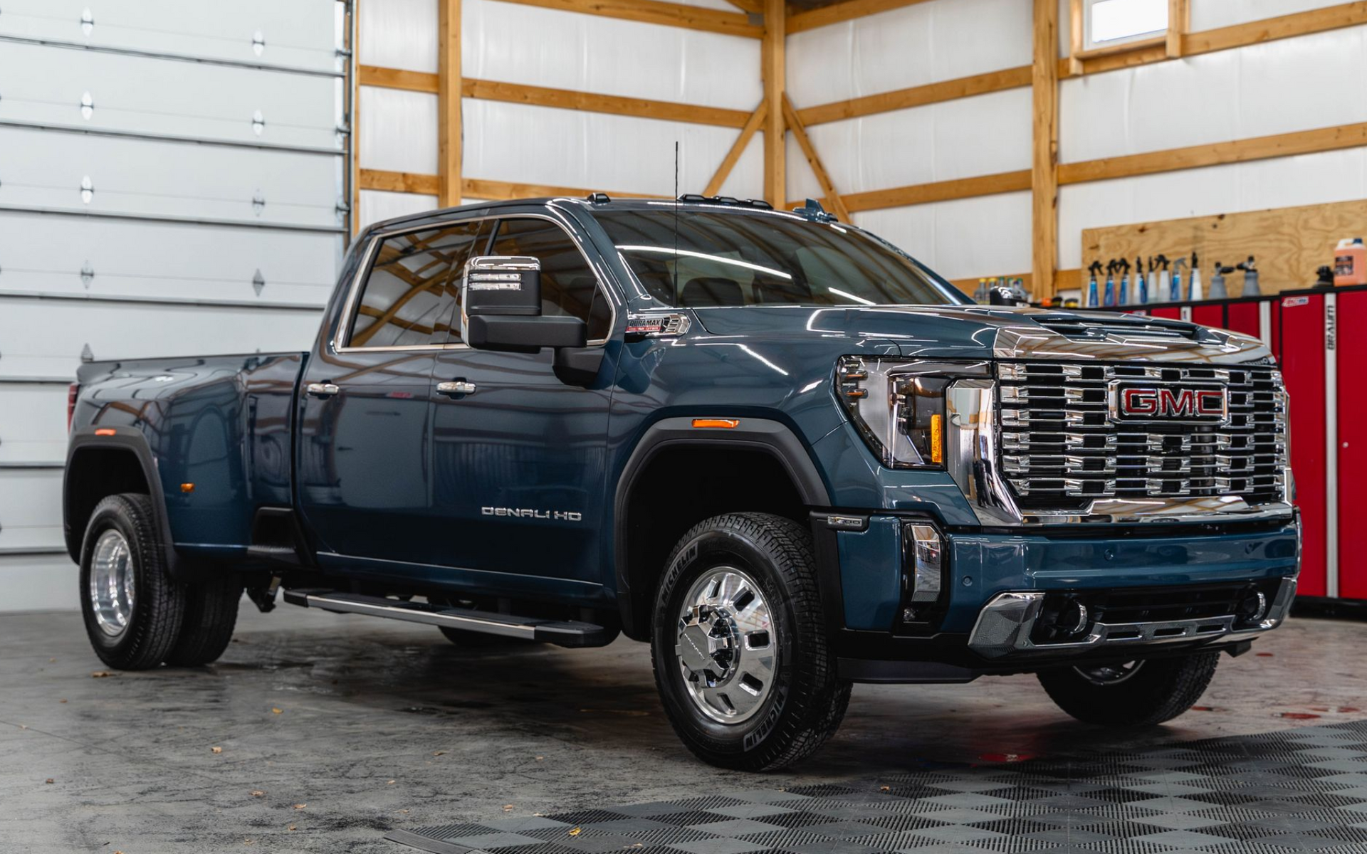 A blue gmc sierra pickup truck is parked in a garage.