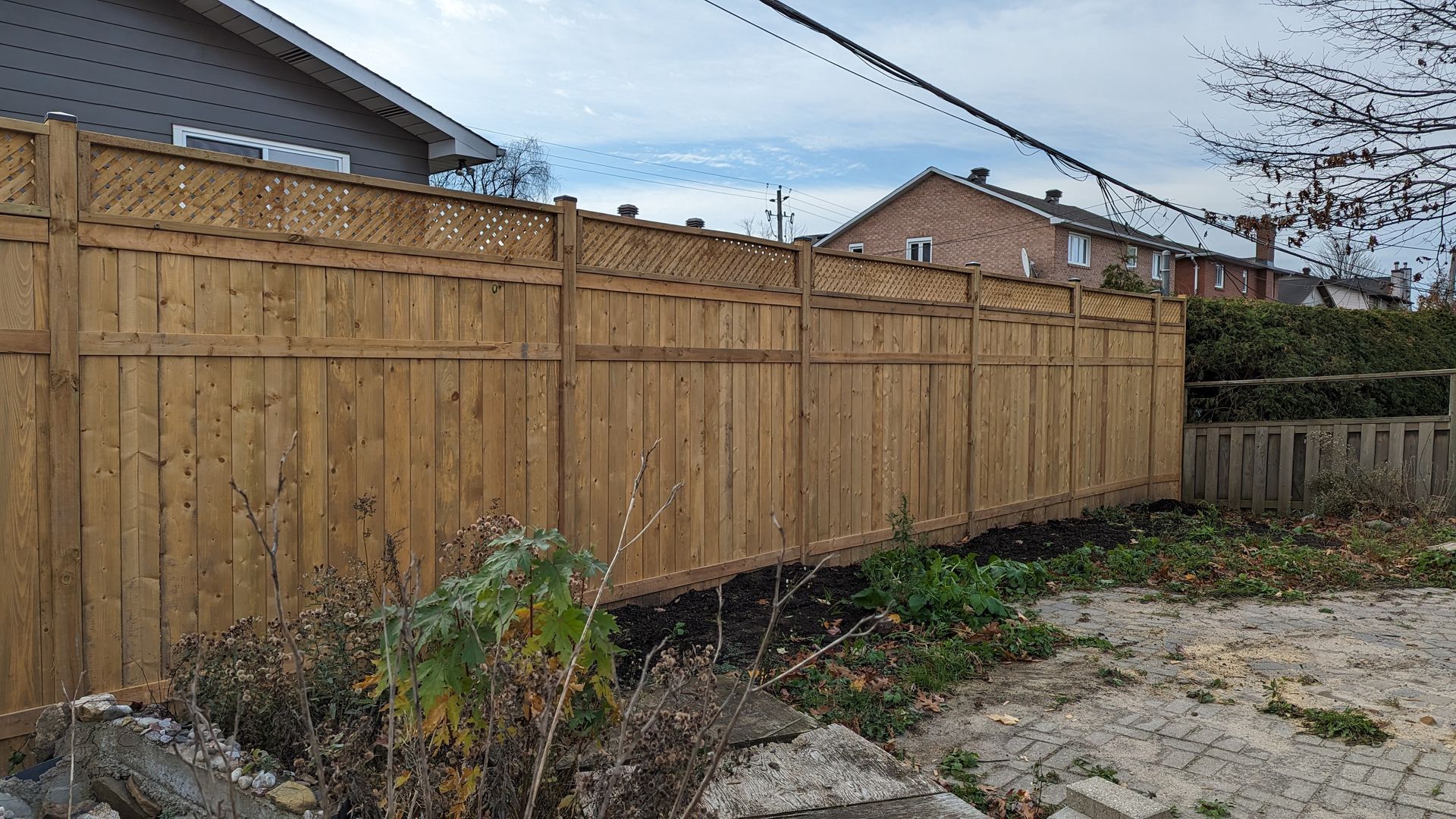 A wooden fence is in the backyard of a house.