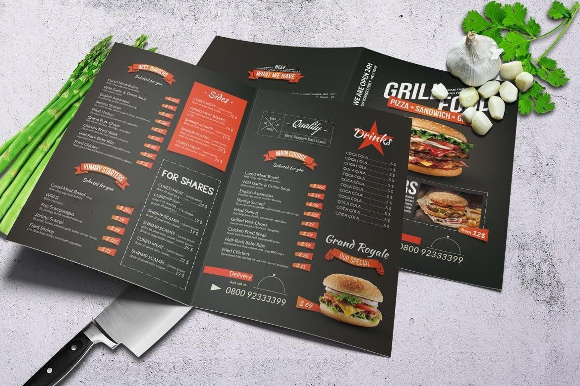 A menu for a restaurant is sitting on a table next to asparagus and garlic.