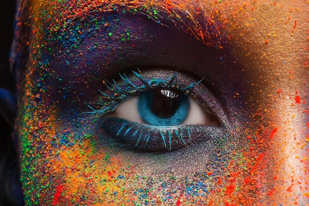 A close up of a woman 's eye with colorful paint on her face.