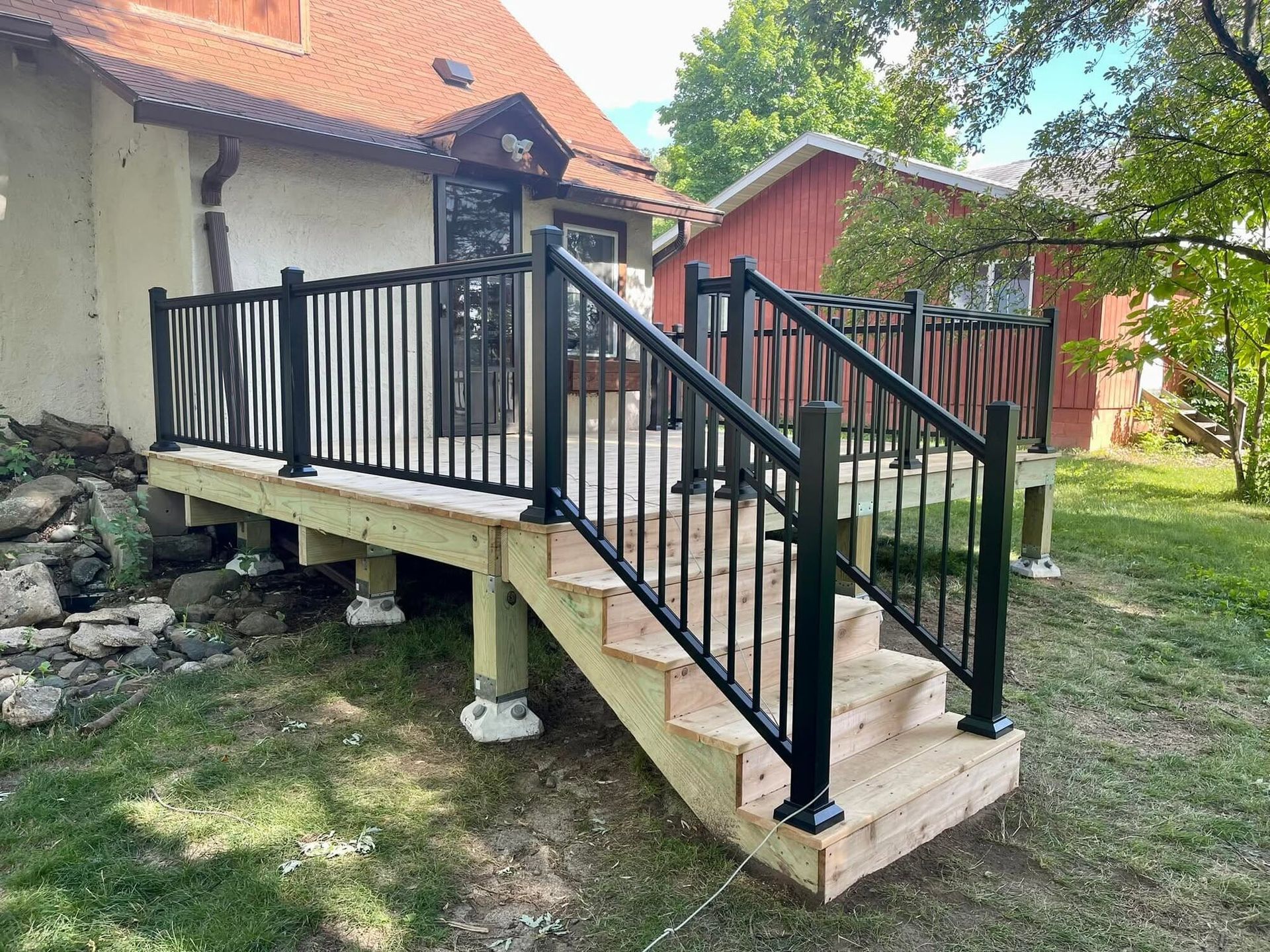 Concrete accessibility ramp with black railings leading to a house entrance outdoors