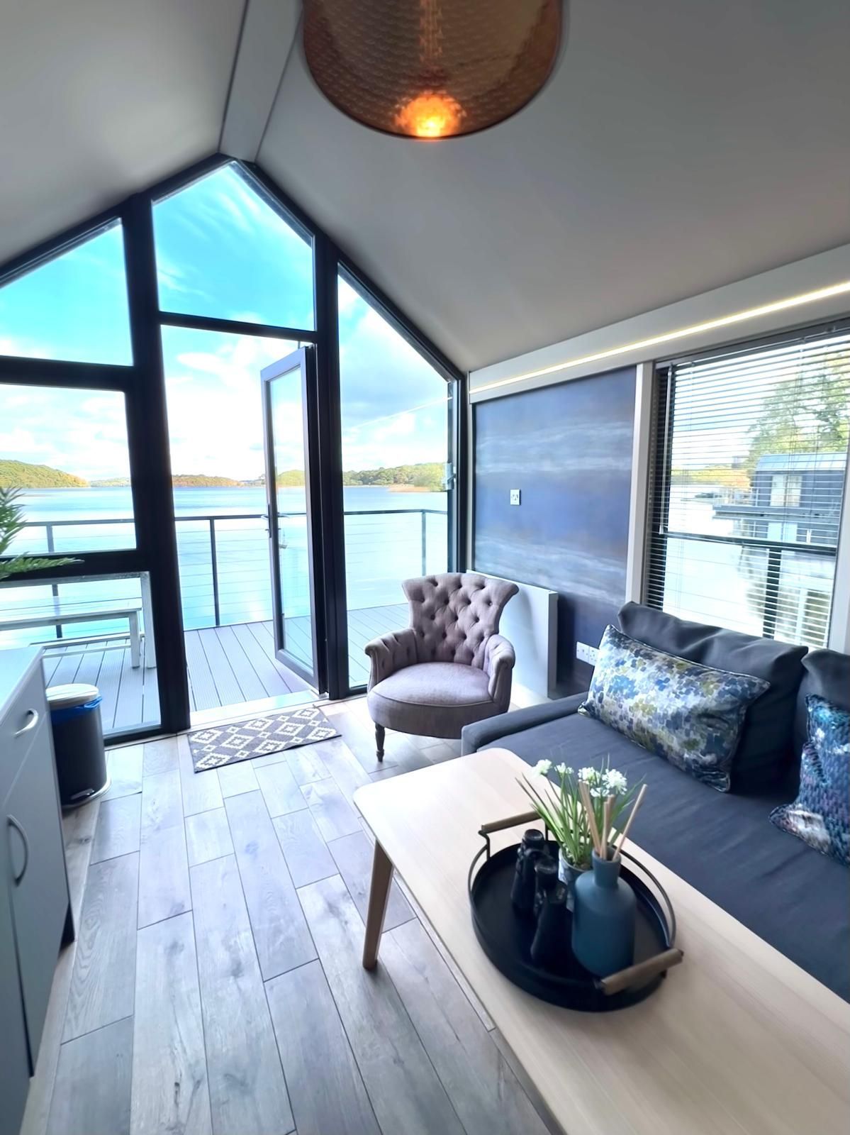 A living room with a couch , chair , coffee table and large windows overlooking a body of water.