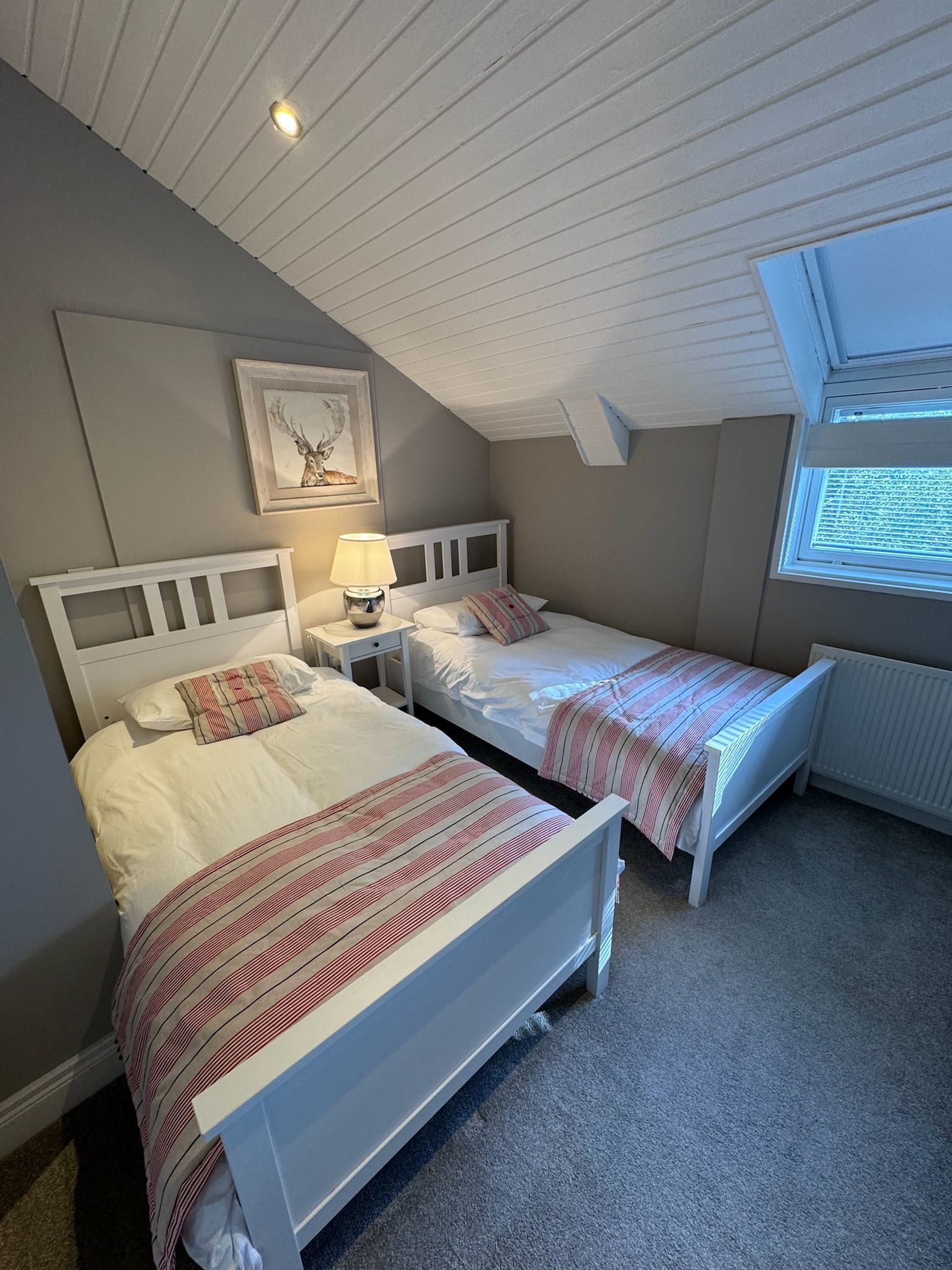 A bedroom with two twin beds and a window.