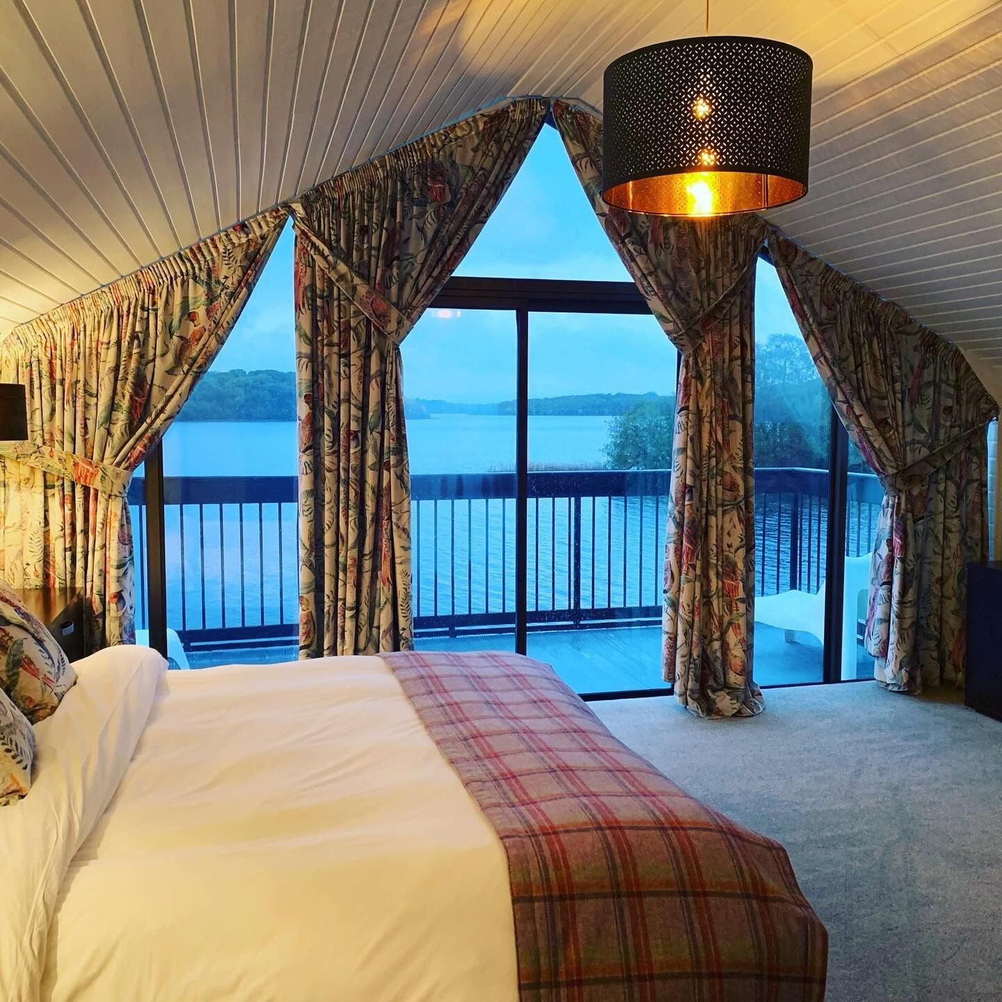 A bedroom with a large bed and a view of a lake