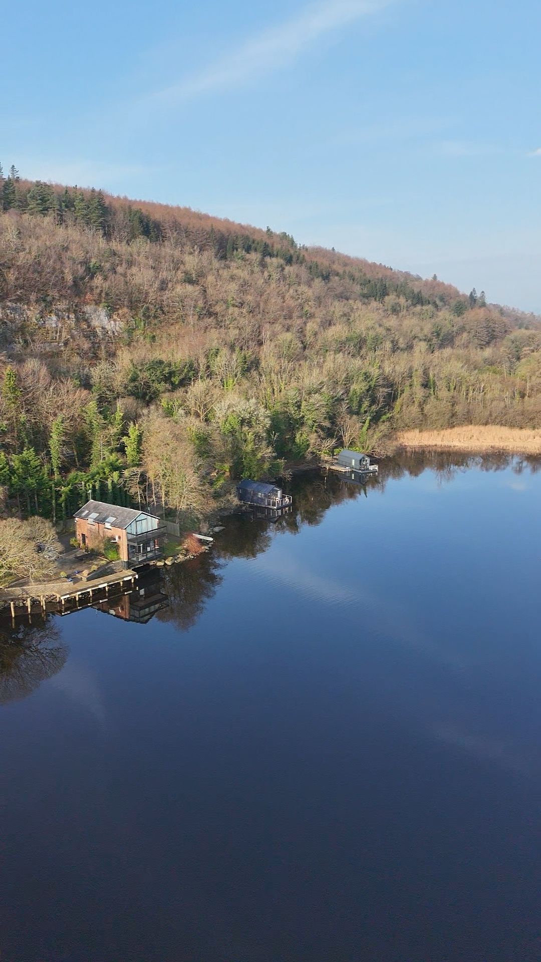 An aerial view of a lake surrounded by trees on a sunny day.