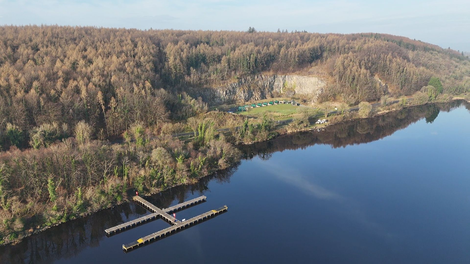 An aerial view of a lake surrounded by trees and a dock.