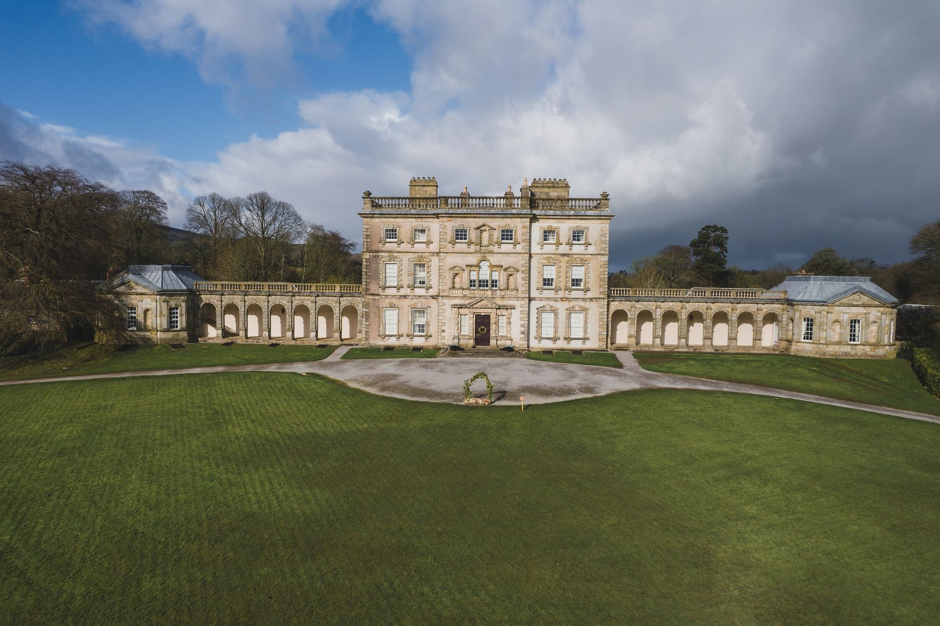 A large building with a lot of windows is sitting on top of a lush green field.