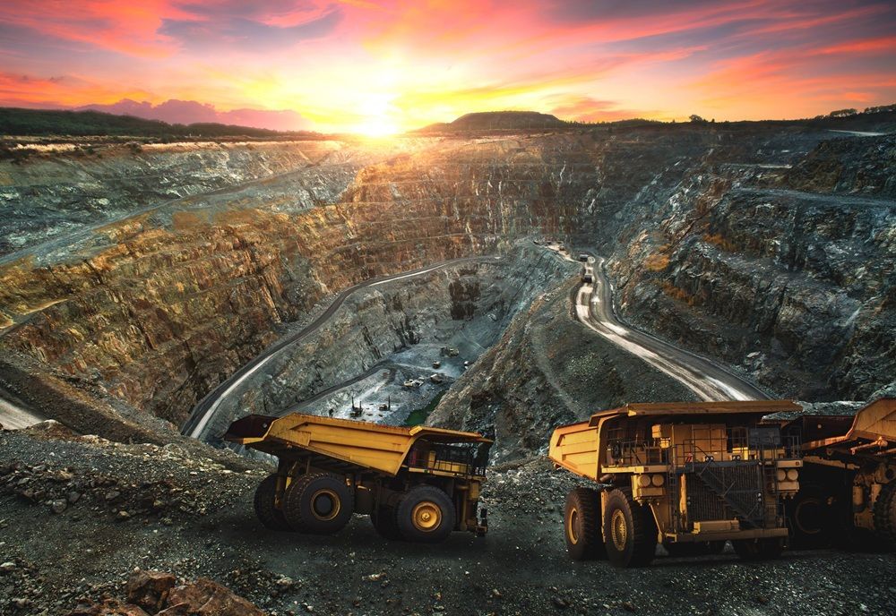 Large yellow mining trucks in a deep open-pit mine at sunset.