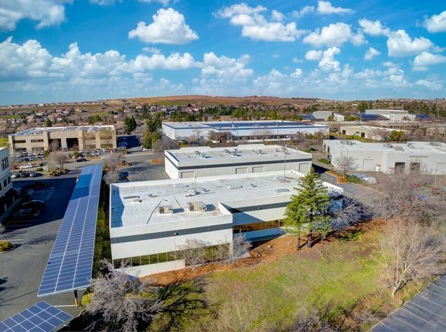 Aerial view of buildings in a suburban area with solar panels and a blue sky.