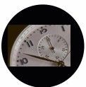 Close-up of a silver watch face with two dials; one small, one large, with black hands pointing to the time.