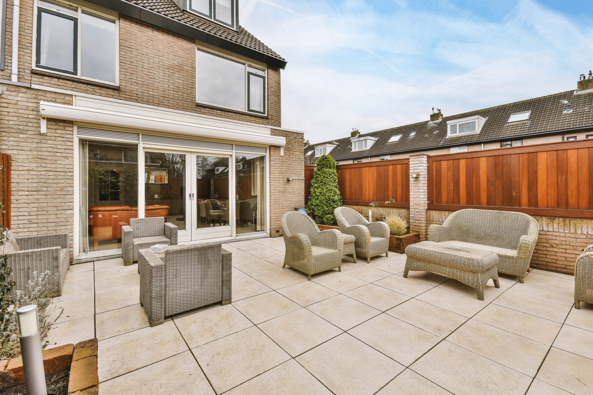 A patio with a couch and chairs in front of a house