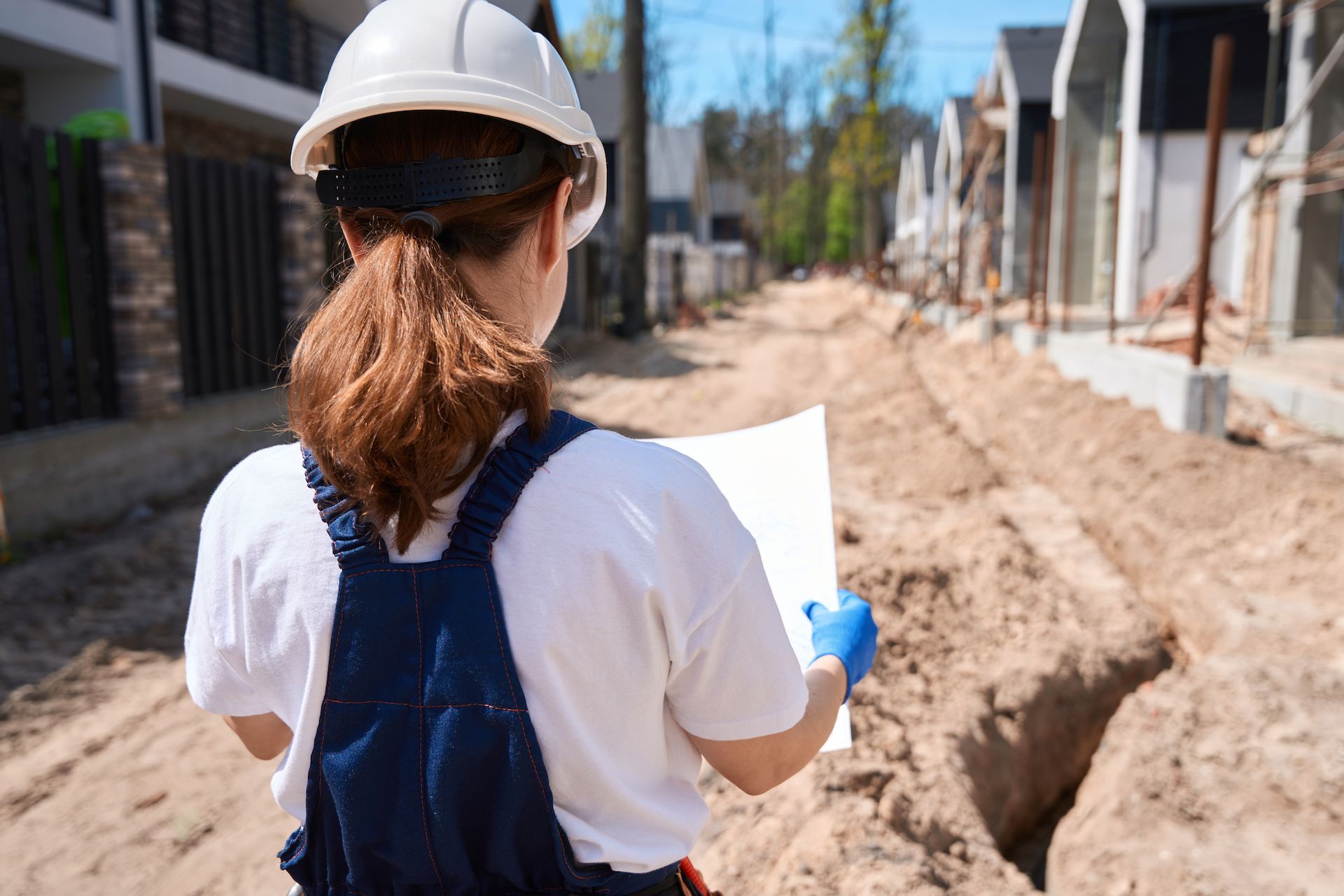 A woman is standing on a construction site looking at a blueprint.