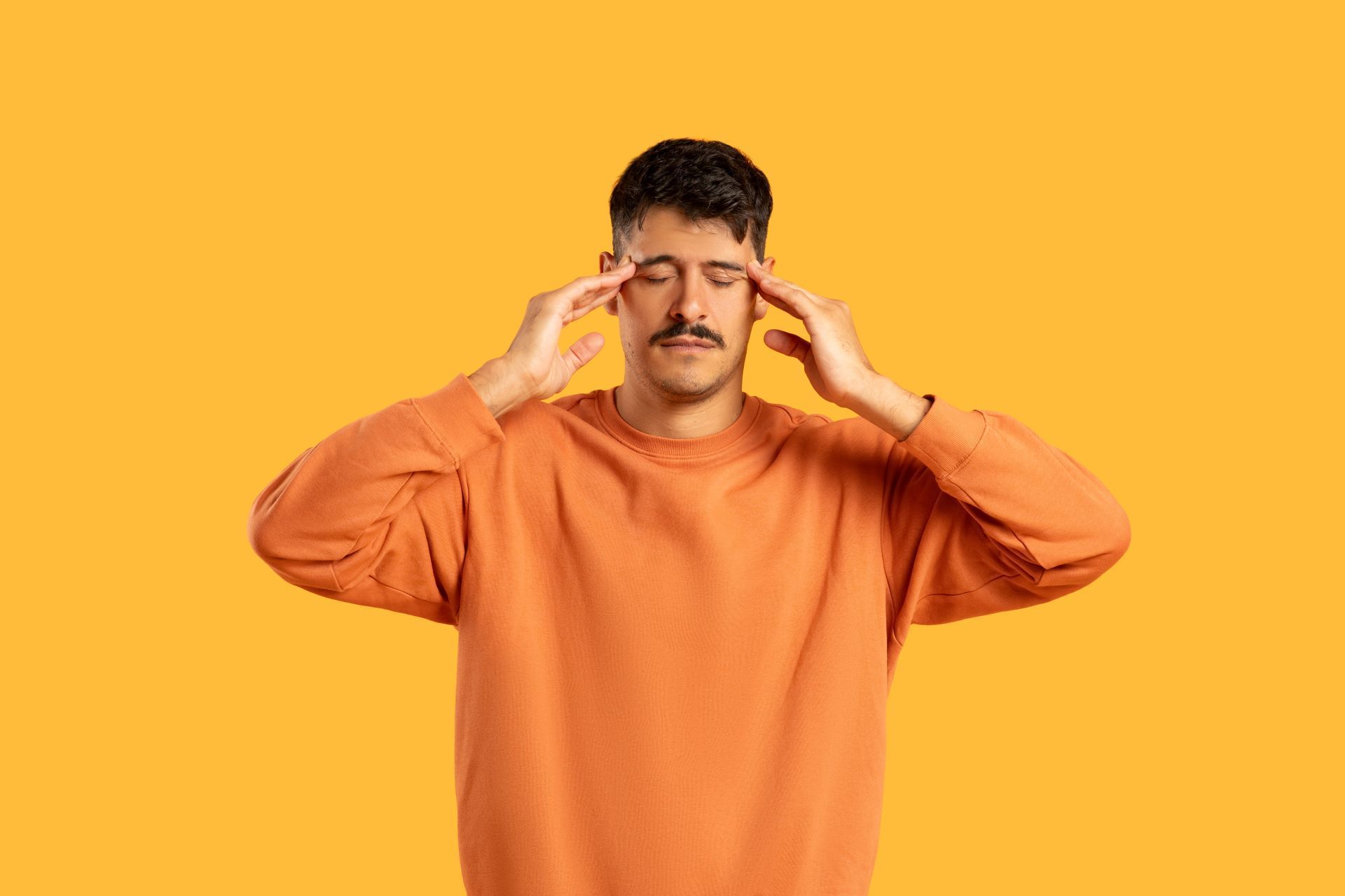 A man with a mustache is holding his head because he has a headache.