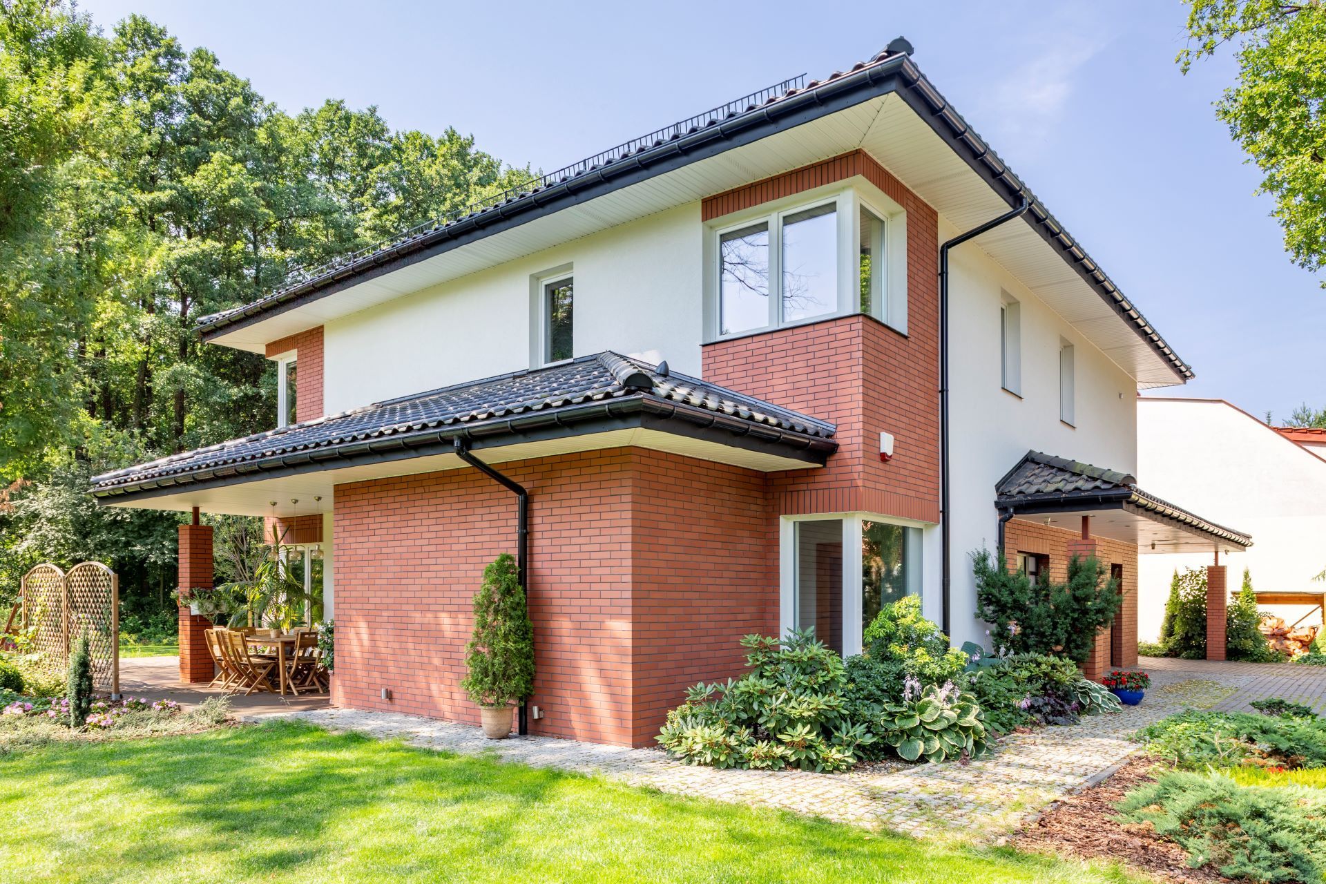A large brick and white house with a lush green lawn in front of it.