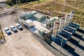 Aerial view of an industrial facility with parked cars, tanks, containers, and storage units on a gravel lot