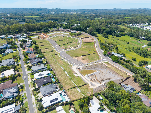 Aerial view of a residential development under construction beside a neighborhood and green landscape