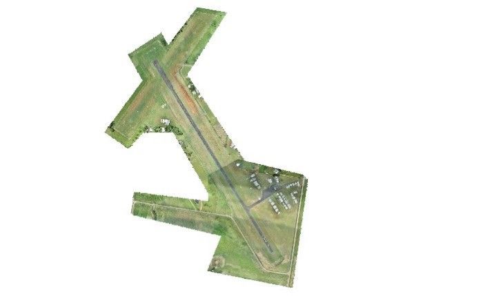 Aerial view of a grassy, X-shaped runway or airfield layout with intersecting paved strips.