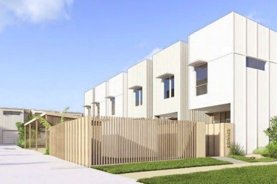 Modern white townhouses with a wooden fence and green lawn under a blue sky