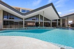 Modern building with a covered patio overlooking a turquoise pool