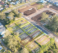 Aerial view of a landscaped site with outlined garden plots and trees near a road.