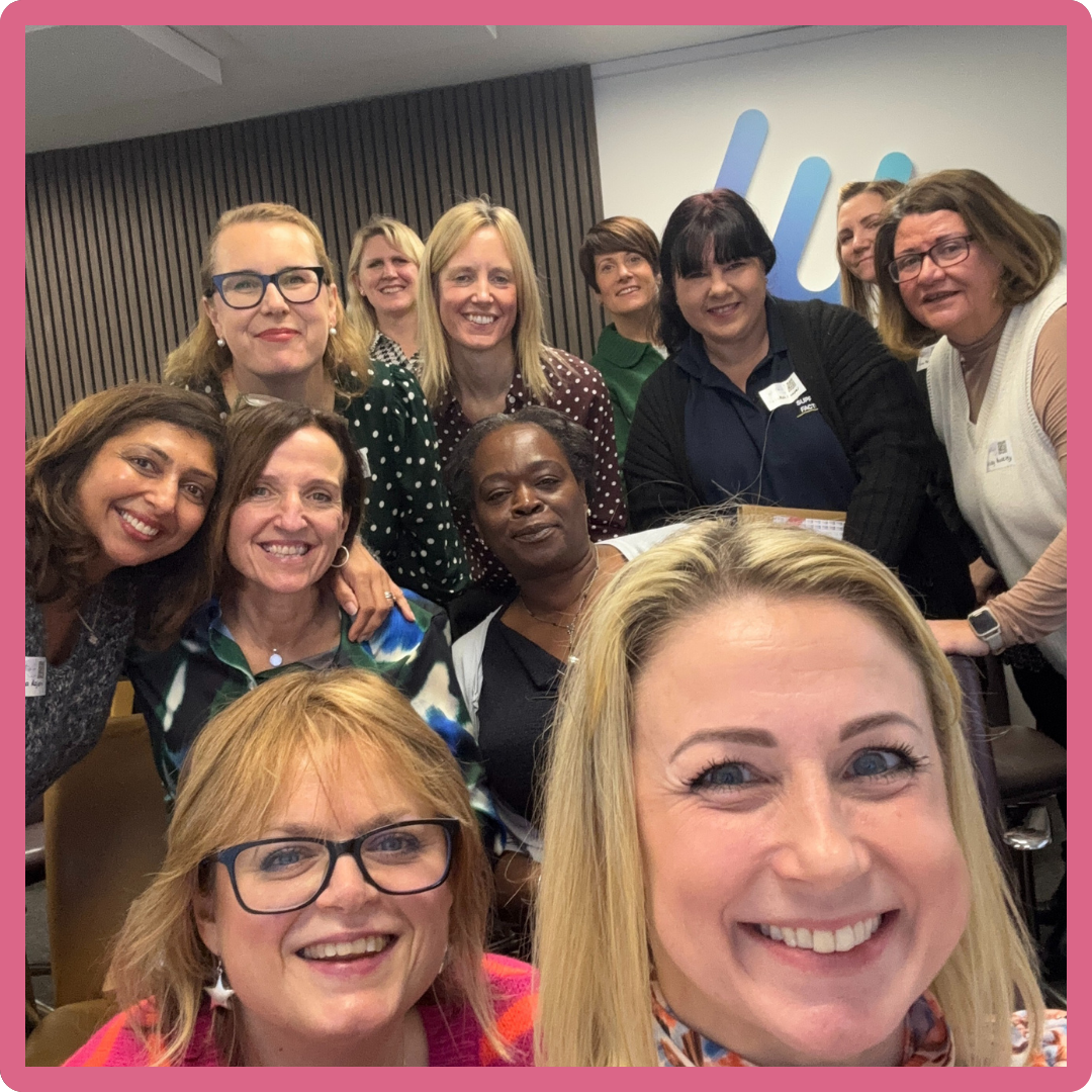 Group of women smiling at the camera in an office setting.