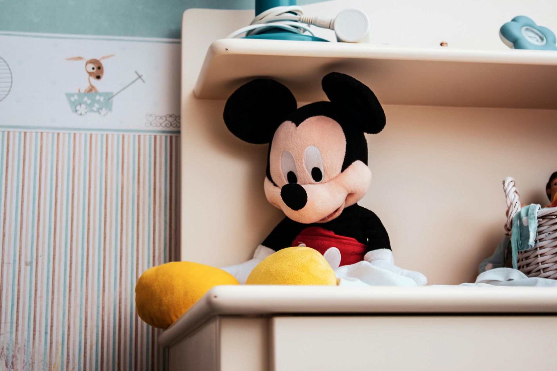 A stuffed mickey mouse is sitting on a shelf