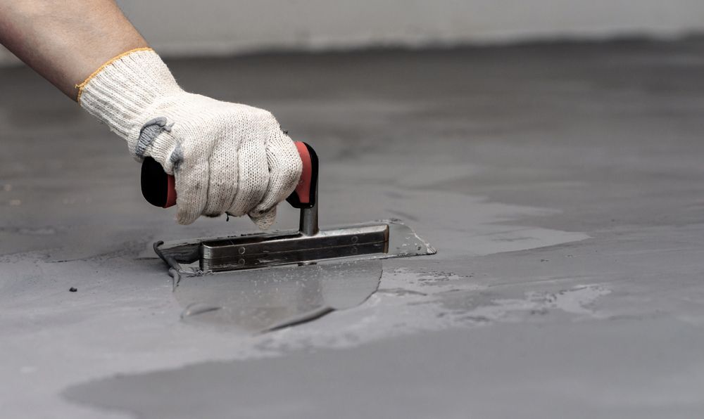 Person in Work Glove Using Trowel to Smooth Wet Concrete on a Floor — Showcase Concrete & Polishing in Moore Park Beach, QLD